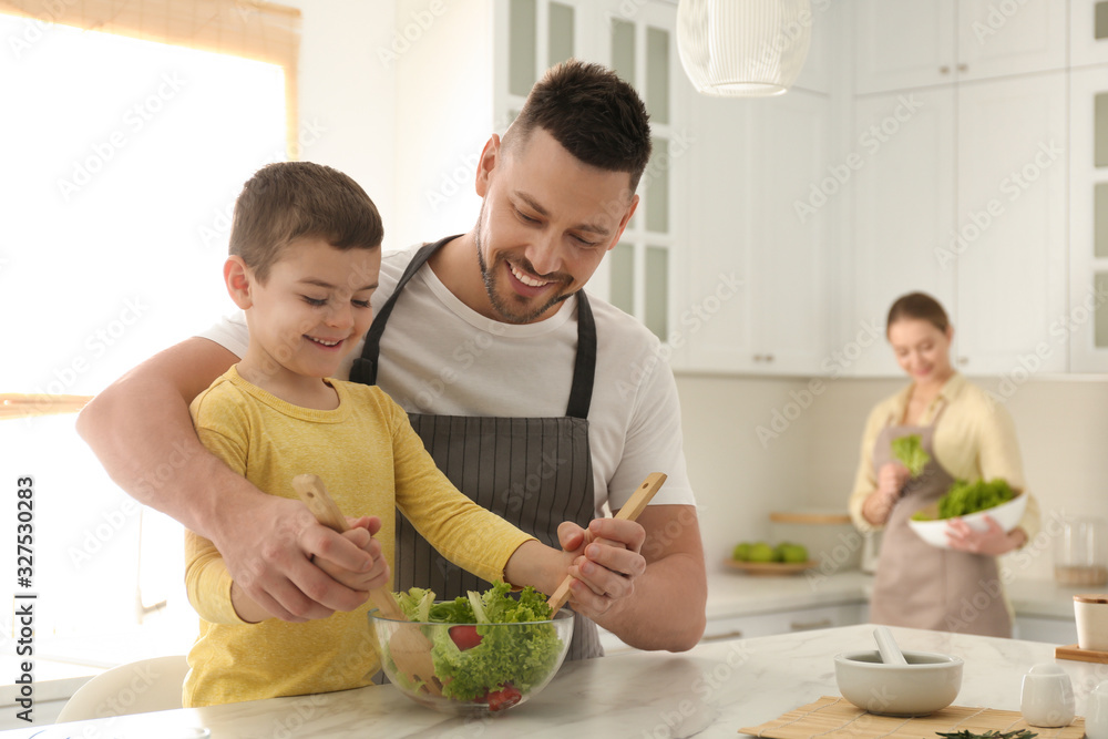 Happy family cooking salad together in kitchen Happy family cooking salad together in kitchen