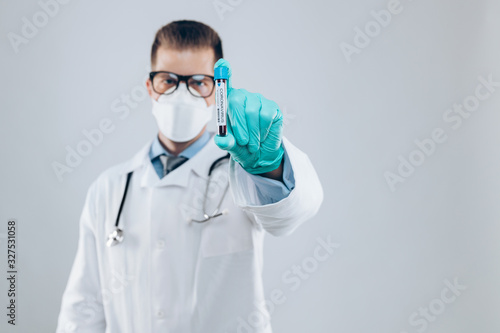 Health worker wearing a respiratory mask, holding the Coronavirus Covid-19 blood bample,