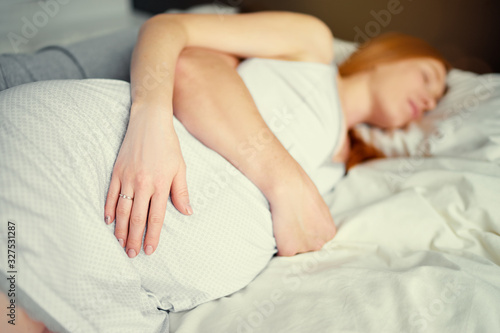 Close up of young pregnant woman sleeping in bed.
