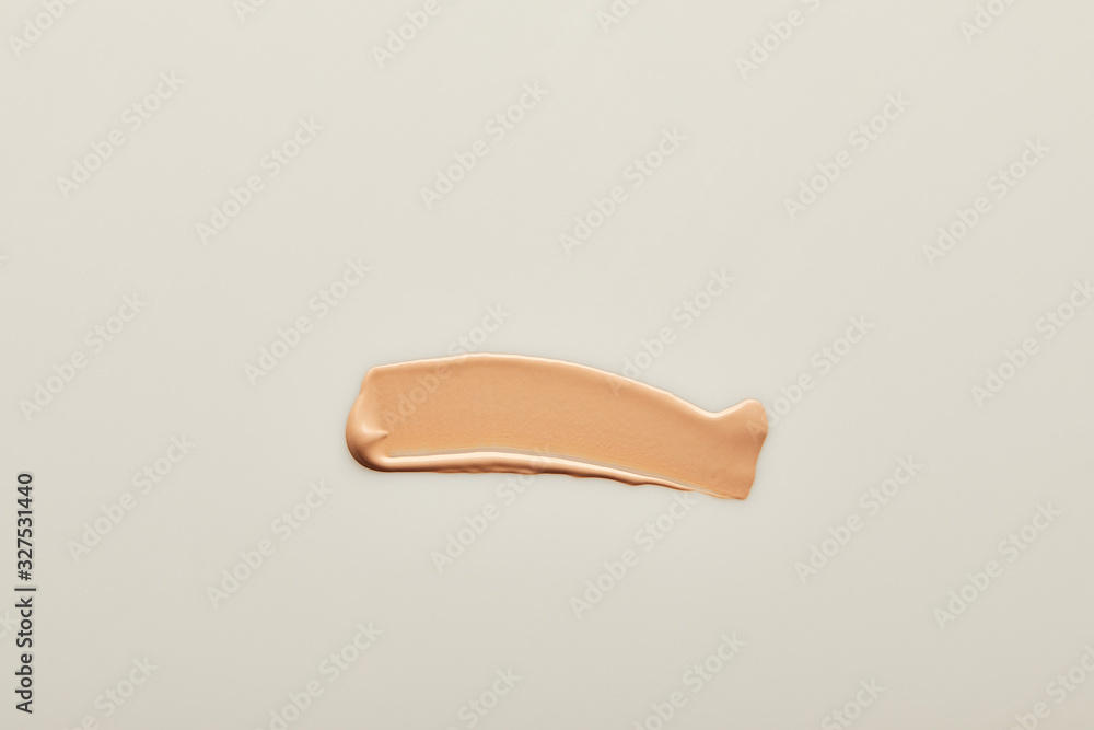 Top view of tone cream brushstroke on grey background Top view of tone cream brushstroke on grey background