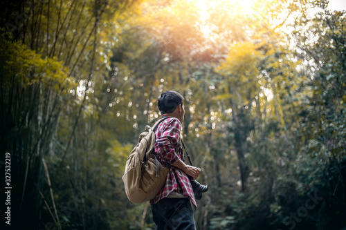 Tourists man standing in bamboo forest with backpack and camera. travel concept.