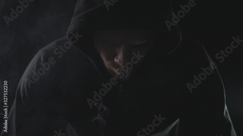 man in black hoodie smoking vape in dark room. blowing smoke photo