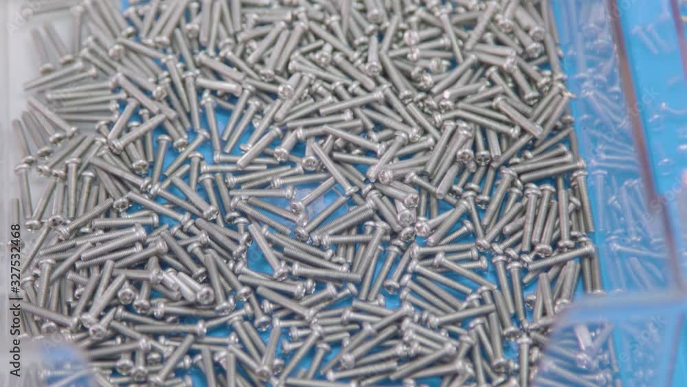 Close Up Of Factory Worker's Hand Picking Up small Screws And Bolts. Industrial Setup Close Up Of Factory Worker's Hand Picking Up small Screws And Bolts. Industrial Setup