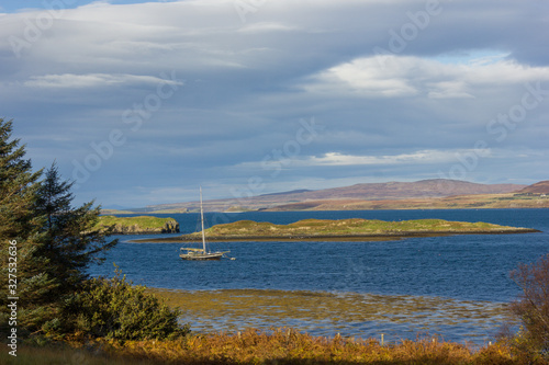 sailboat in the middle of a bay  sea of an intense blue  islets with abundant grass