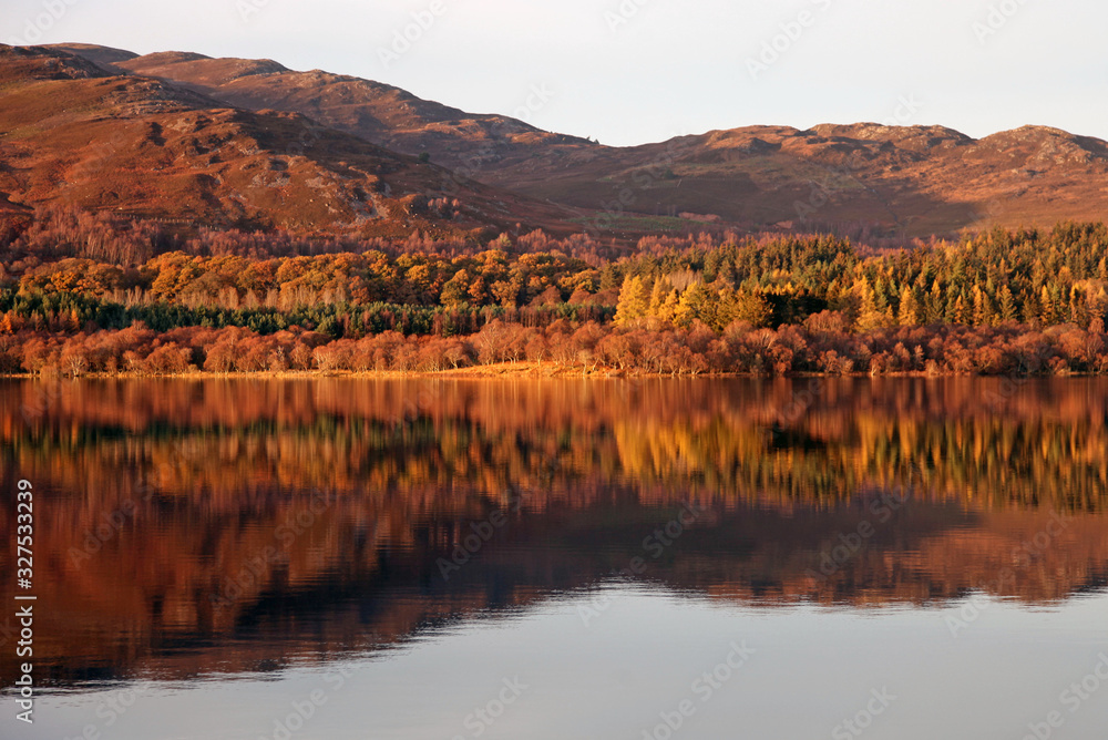 Reflections of Autumn colours in Loch Alvie, Cairngorms, Scotland