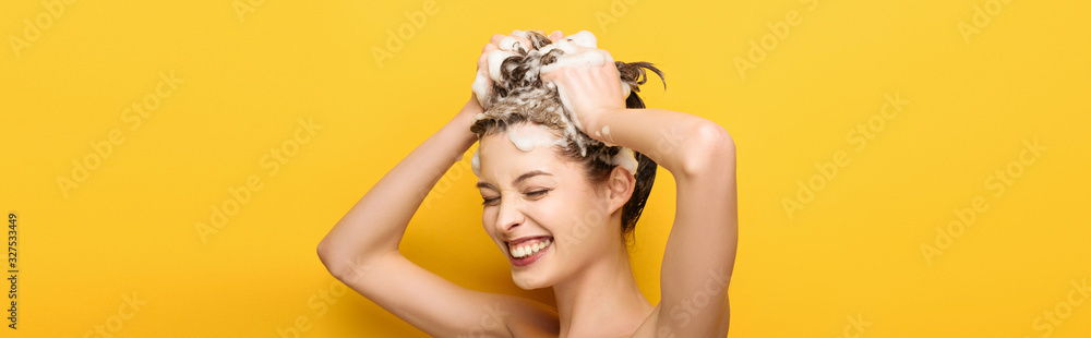 panoramic shot of happy girl with closed eyes washing hair on yellow background - obrazy, fototapety, plakaty 