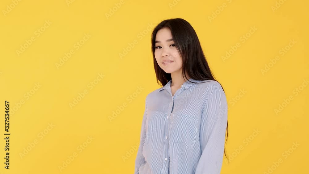 Young Asian girl on yellow background posing and flirting and smiling at camera Young Asian girl on yellow background posing and flirting and smiling at camera