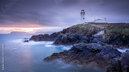 Twilight yields to dawn, sunrise at Fanad Head Lighthouse with blurred water of Atlantic Ocean. Wild Atlantic Way, Donegal, Ireland