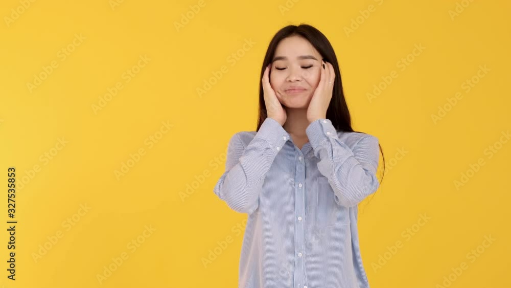 Young Asian girl on yellow background smiling and looking at camera. blue shirt Young Asian girl on yellow background smiling and looking at camera. blue shirt