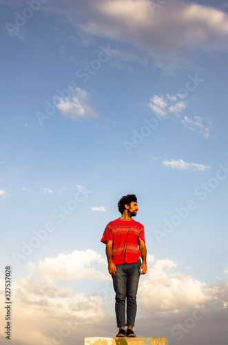 young man standing with the sky in the background