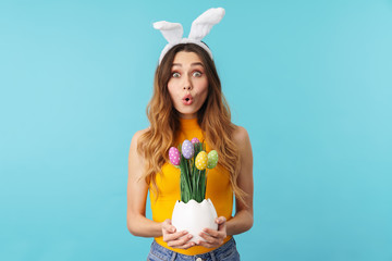 Portrait of young woman wearing bunny ears holding painted easter eggs