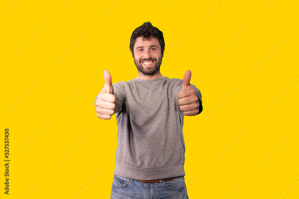 Young man with thumbs up on yellow background. Positive attitude and trust. Young man with thumbs up on yellow background. Positive attitude and trust.