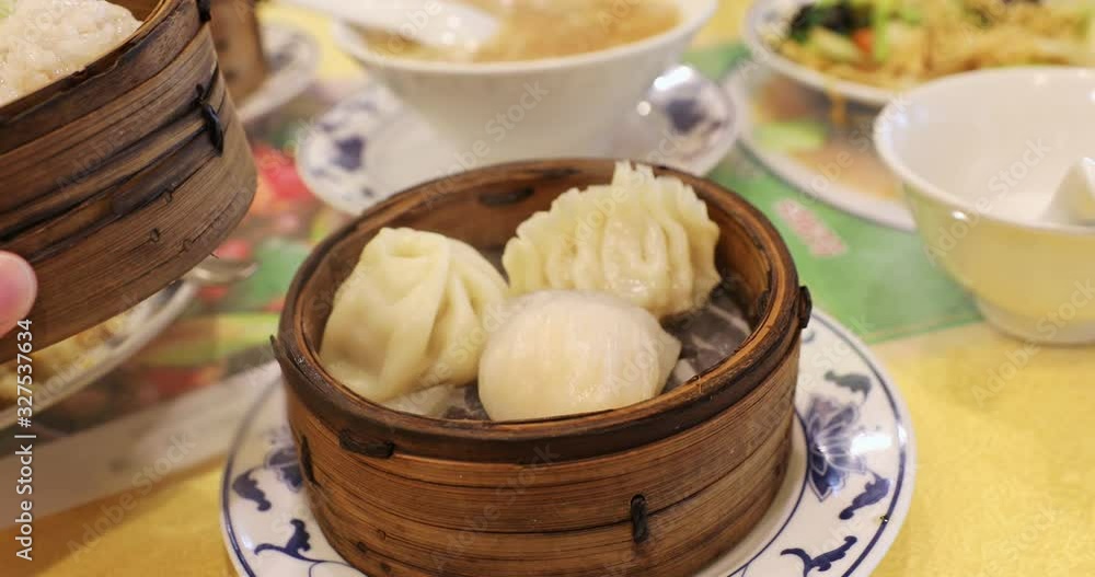 Chinese restaurant at Yokohama Chinatown in Japan with asian steaming dumplings in a wooden steamer, steamed buns, ramen, noodles, rice, soy and hand taking steaming dumplings. Chinese restaurant at Yokohama Chinatown in Japan with asian steaming dumplings in a wooden steamer, steamed buns, ramen, noodles, rice, soy and hand taking steaming dumplings.