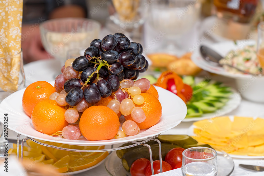 Fruits-grapes, oranges, tangerines, lemon on holiday table Fruits-grapes, oranges, tangerines, lemon on holiday table