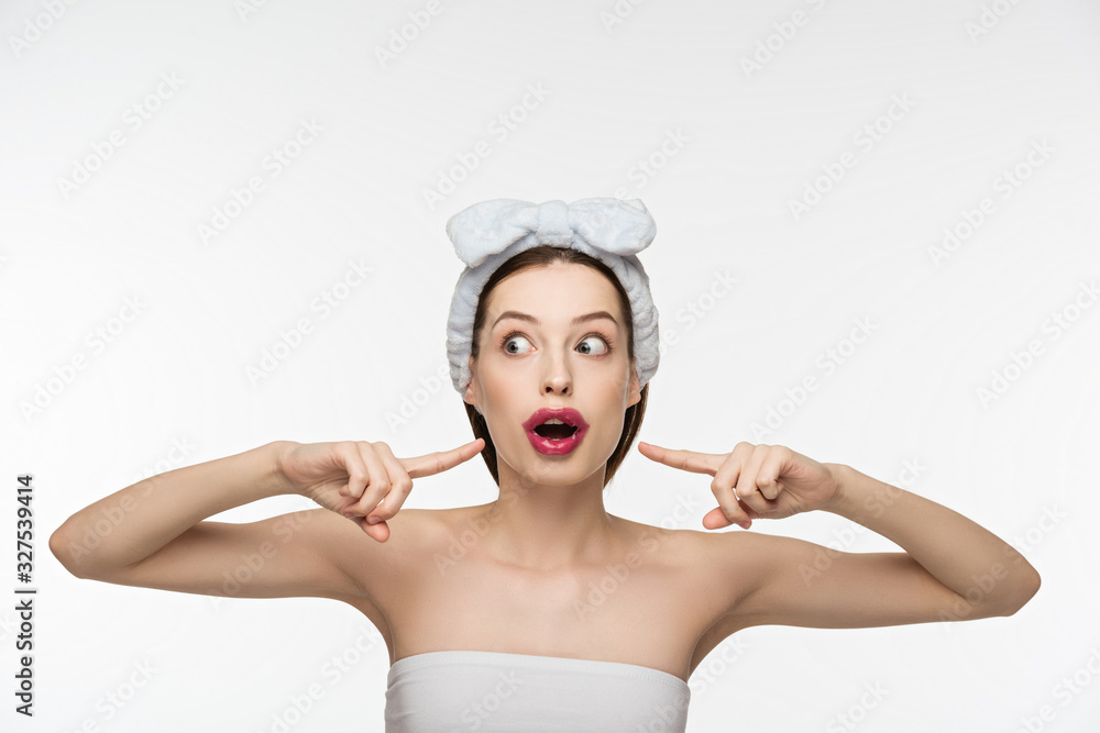 surprised girl pointing with fingers at collagen patch on lips isolated on white surprised girl pointing with fingers at collagen patch on lips isolated on white