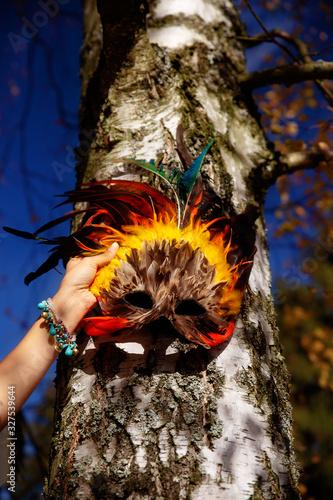 colorful feather face mask in woman hand.