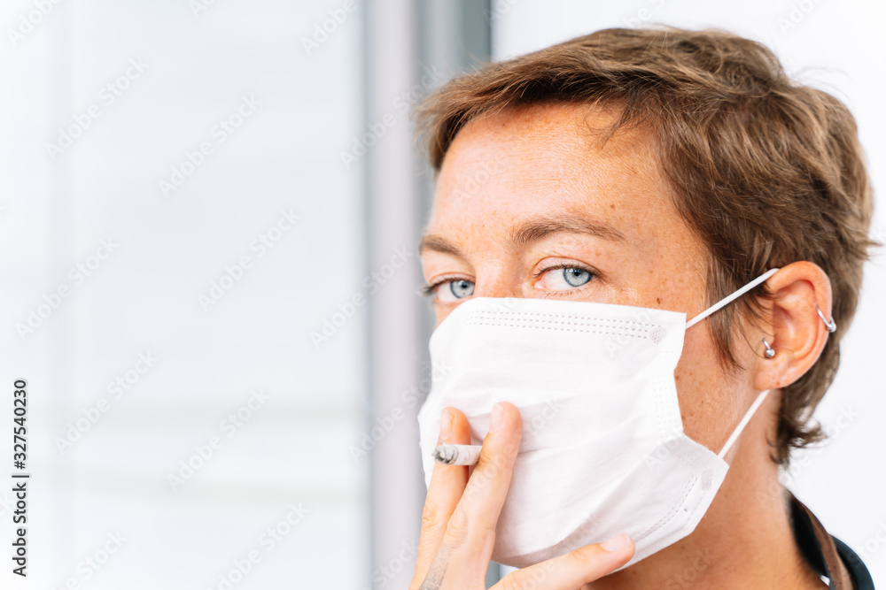 portrait of a young caucasian girl with headphones and a medical mask and smoking a cigarrette on white background portrait of a young caucasian girl with headphones and a medical mask and smoking a cigarrette on white background