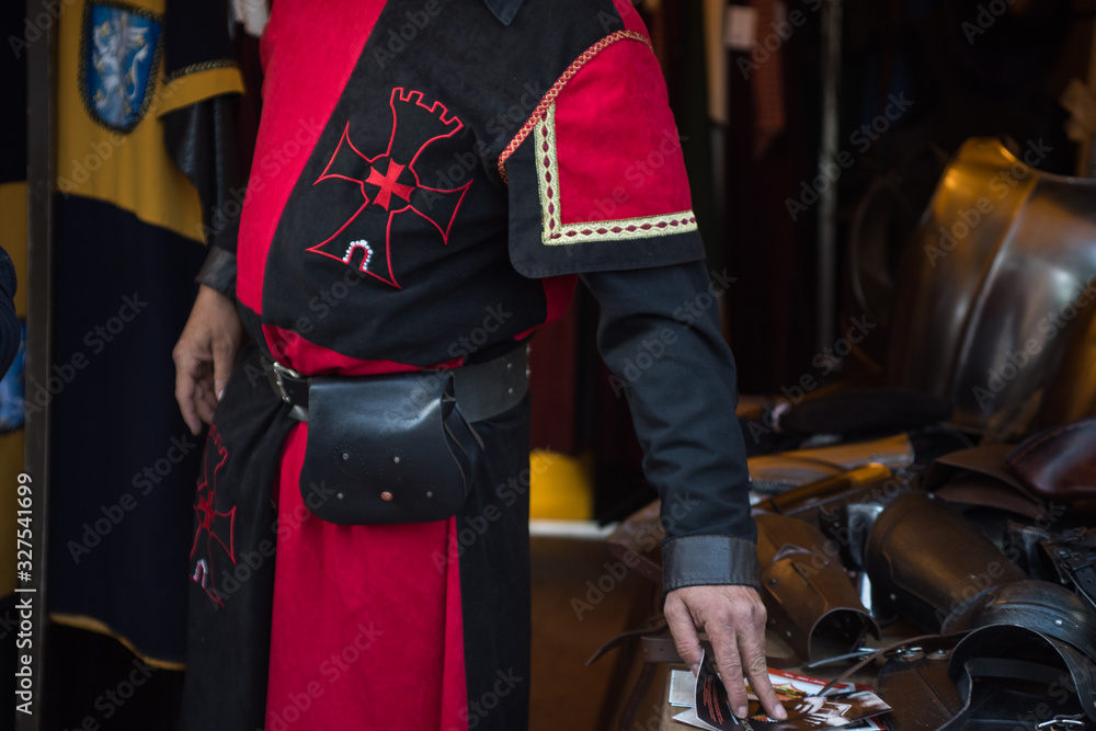 Man wear medieval uniform at the market stall. Red and black suit on a history revival recreation of the lovers of Teruel
