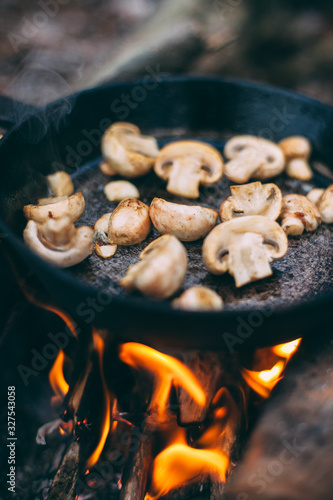 Fried mushrooms in a pan in the forest. Fried food in nature. Picnic in the winter forest. Cooking on an open fire. Champignon on a fire..