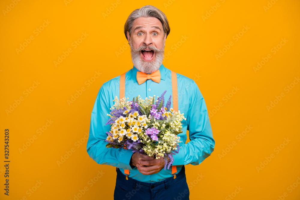 Surprise. Photo of handsome trendy white haired grandpa open mouth hold fresh bunch wildflowers girlfriend wife date wear blue shirt suspenders bow tie isolated yellow color background Surprise. Photo of handsome trendy white haired grandpa open mouth hold fresh bunch wildflowers girlfriend wife date wear blue shirt suspenders bow tie isolated yellow color background