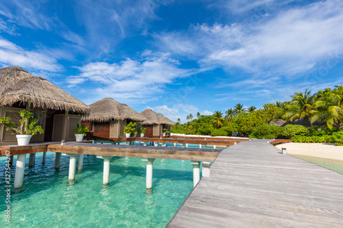 Exotic landscape of Maldives beach. Tropical panorama, luxury water villa resort with wooden pier or jetty. Luxury travel destination background for summer holiday and vacation concept. © icemanphotos