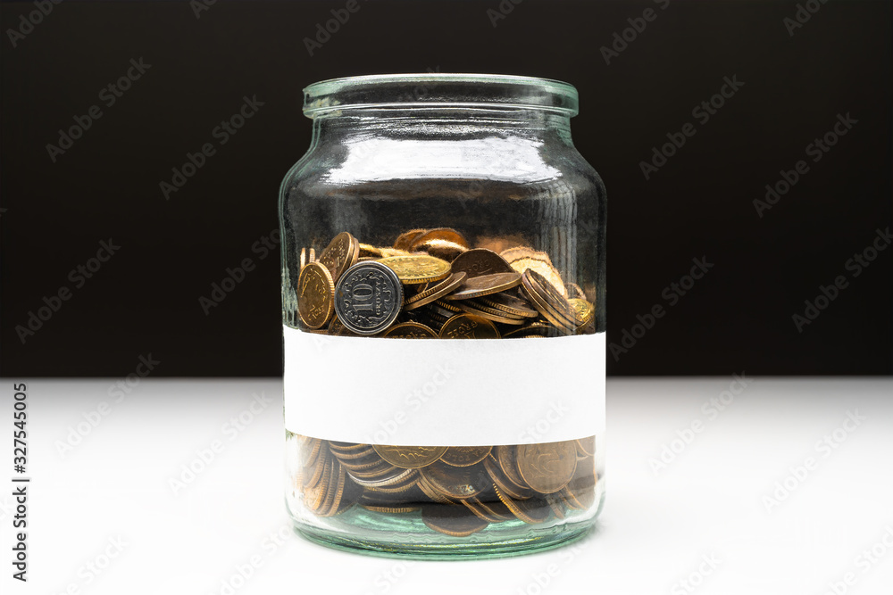 Coins in a jar with blank white label. Savings abstract concept. Copy space. Coins in a jar with blank white label. Savings abstract concept. Copy space.