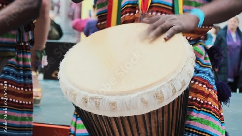 Close-up African s hands playing on djembe drum close up. Musician beats rhythm on african drums. Black artists hit the drums with their hands. Girls dancers dance samba. Brazilian carnival atmosphere