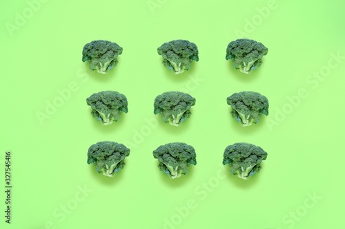 Broccoli on a green background. Seamless food pattern in a minimalistic style, photo collage. Concept of diet, healthy food. Top view, flat lay.