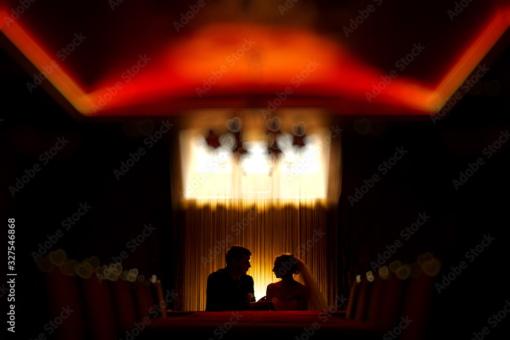 silhouette man and woman on the romantic date in evening cafe. couple in love .  bride and groom tenderness looks each other indoor night portrait with lamp. love story background. 
