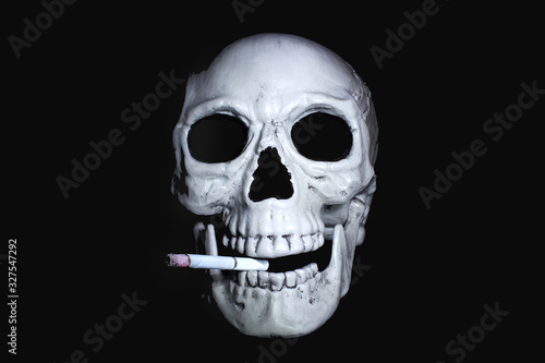  Human skull with a smoking cigarette in his mouth looking out of the dark