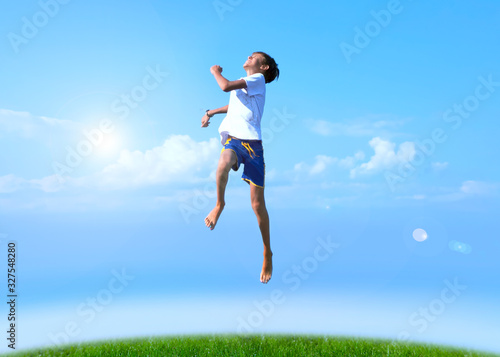 A boy jumps on a summer background of blue sky © SlayStorm