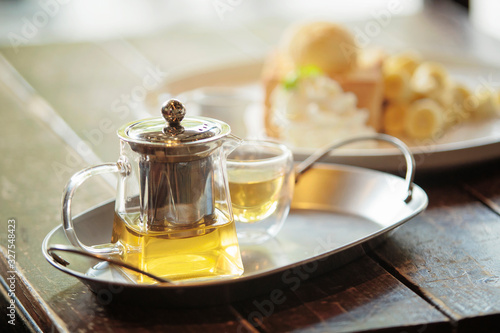 Transparent glass teapot and cup of tea on the stainless steel tray placed