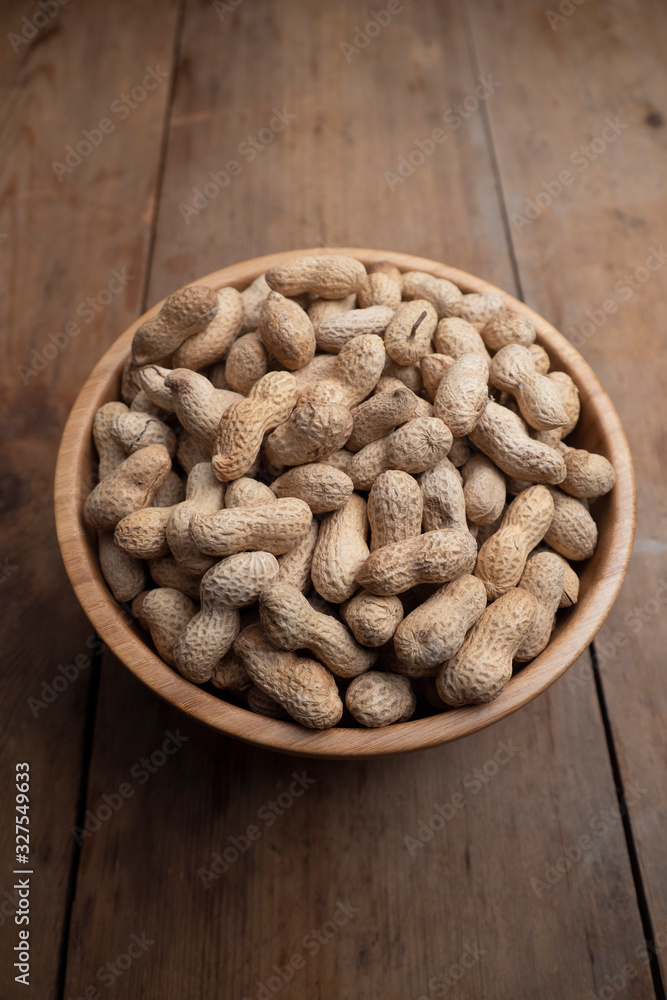 Wooden bowl of roasted peanuts in shells Wooden bowl of roasted peanuts in shells