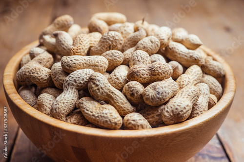 Wooden bowl of roasted peanuts in shells