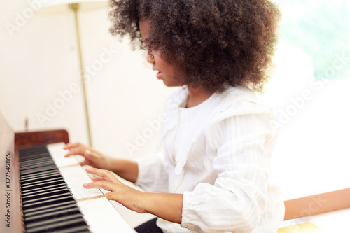 Beautiful African girl playing piano keyboard in classroom learning at room.