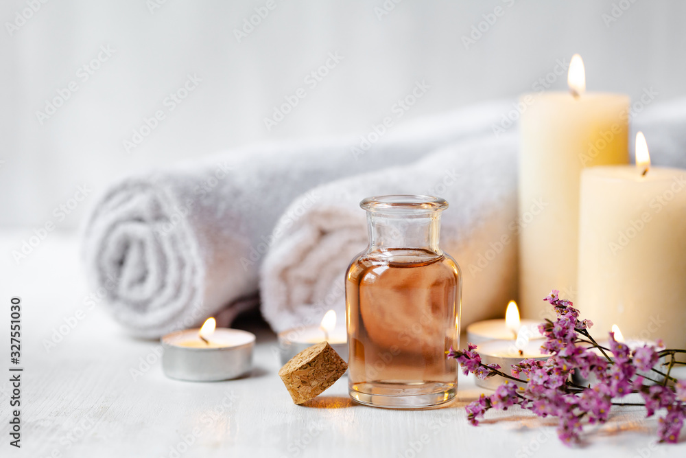Concept of spa treatment in salon. Natural organic oil, towel, candles as decor. Atmosphere of relax, serenity and pleasure. Anti-stress and detox procedure. Luxury lifestyle. White wooden background - obrazy, fototapety, plakaty 