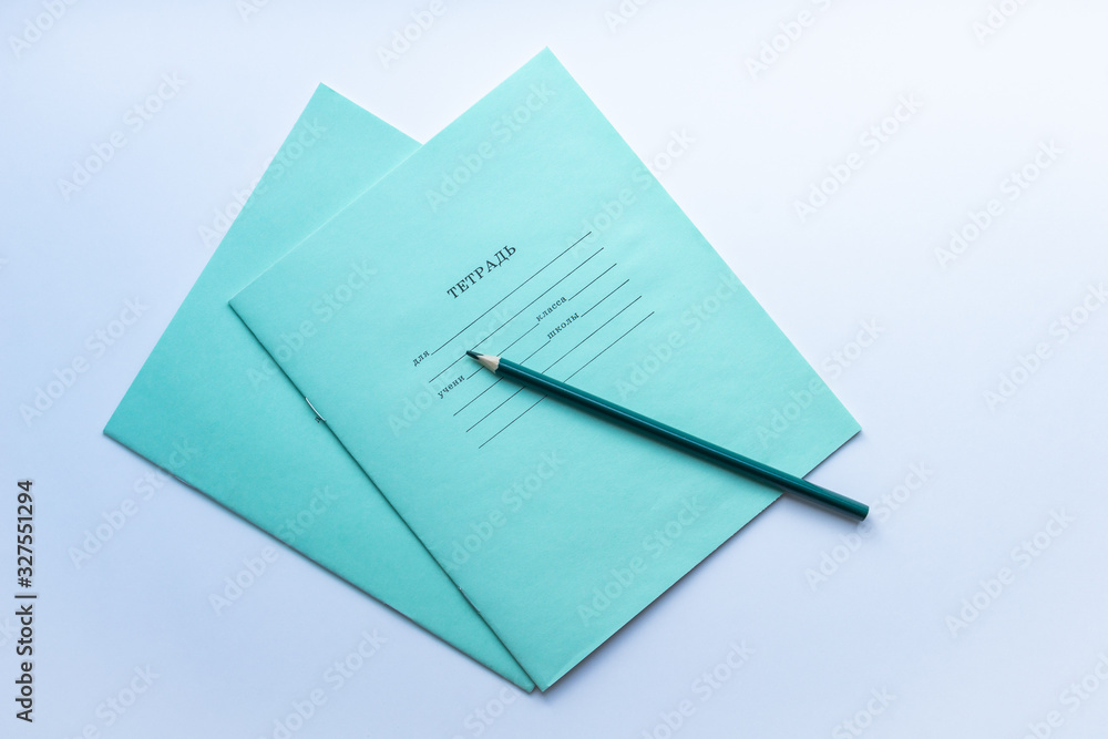Top view of two pupils copybooks with dark green pencil on white background. Concept of education, minimalism. Top view of two pupils copybooks with dark green pencil on white background. Concept of education, minimalism.