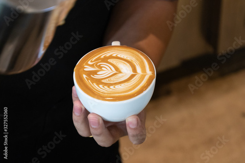 Latte art by barista focus in milk and coffee.Professional barista pouring steamed milk into coffee cup making beautiful latte art. photo