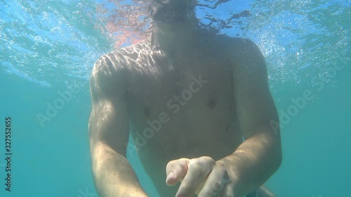 A video filmed underwater that shows a guy diving and swimming underwater  photo