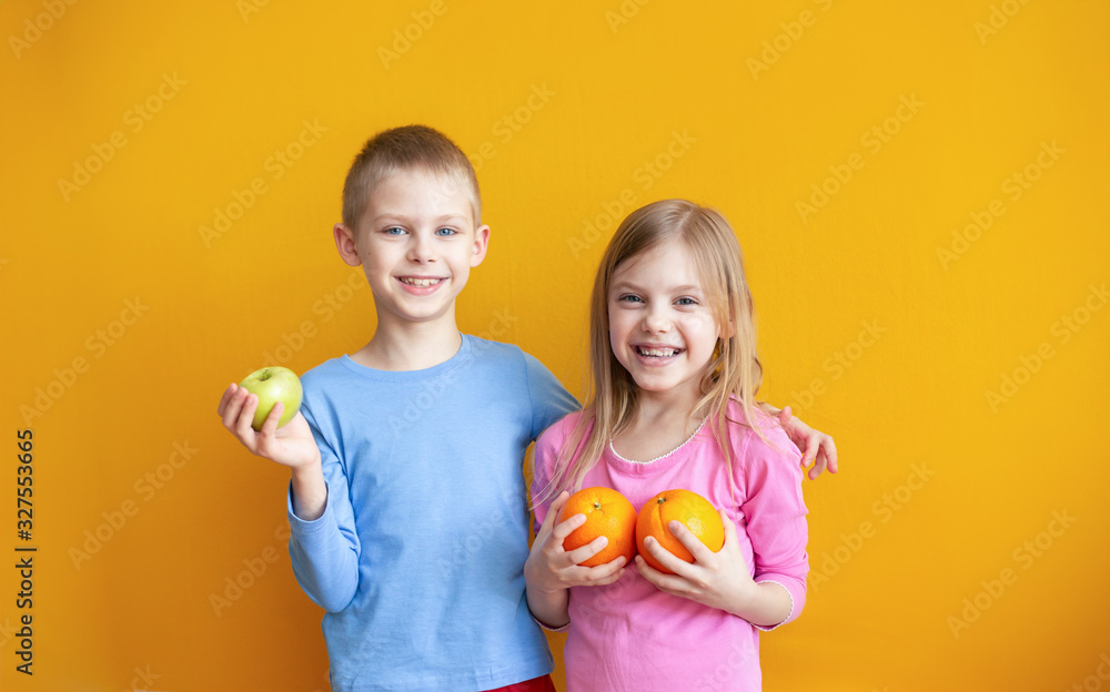 cute kids on an orange background with fruit play, put on their heads and laugh cute kids on an orange background with fruit play, put on their heads and laugh
