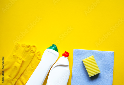 Cleaning supplies on a yellow background. Detergents for cleaning or disinfecting the room. Plastic bottles and Rubber Gloves and Rag  Sponge for Cleaning with Copy Space and  Top View.