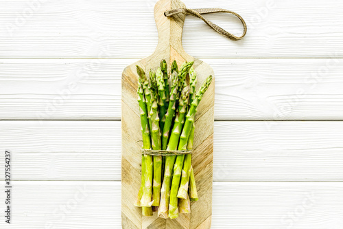 Cooking asparagus. Bunch steams on cutting board on white wooden background top-down copy space