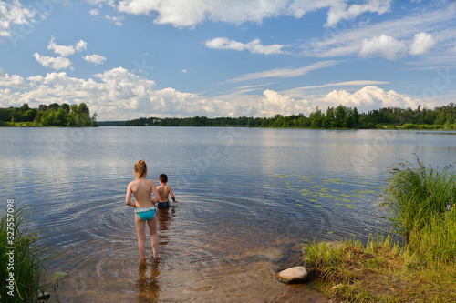 little girl and boy swimming in summer lake