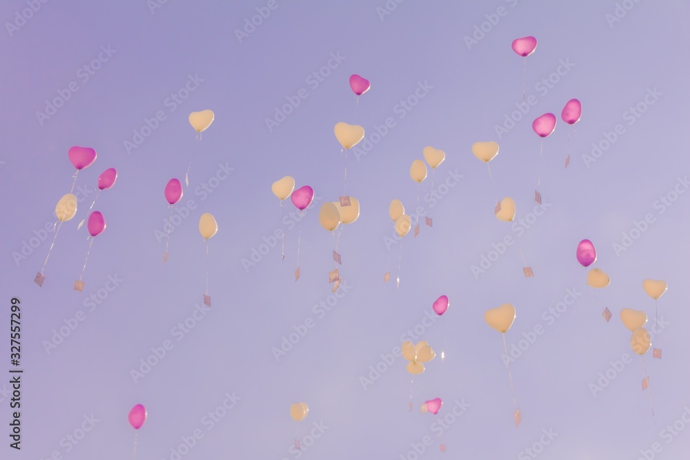 Heart love balloons fly into purple sky with ceremony wishes. Romantic symbol of future partnership. Group of beautiful heart ballons with congratulations cards at wedding party or valentines day