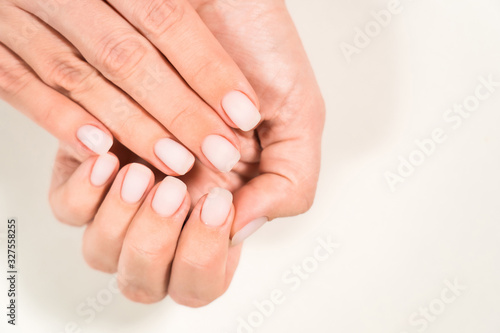 Closeup top view photography of two beautiful manicured female hands. Woman with fresh natural pink pastel matte nails.