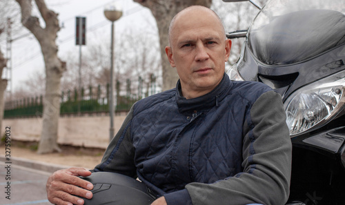 Portrait of a serious young man next to a motorcycle