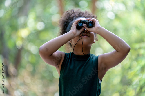 Little African American Girl with Binoculars during Hiking in Forest. © pigprox
