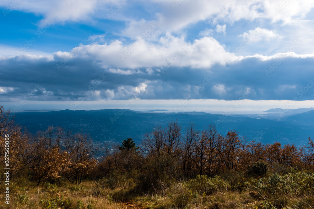 Obraz premium The panoramic view of Côte d'Azur Alps mountains under the cloudy sky and the Meditarrenean sea coastline in the horizon