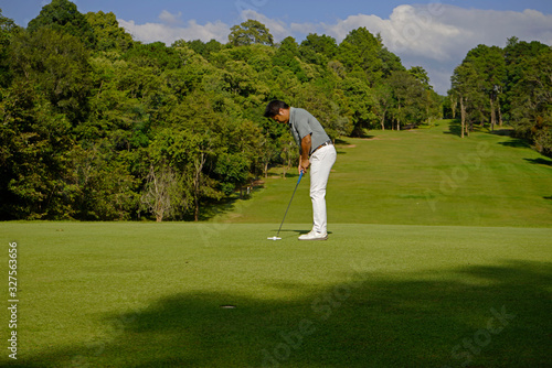 Golfer putting golf in beautiful golf course