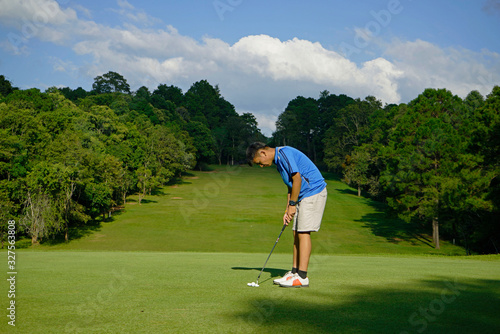 Golfer putting golf in beautiful golf course.